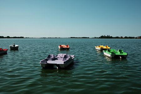 Colorful pedal boats and a small rowboat floating on the peaceful lake surface in Palic, Serbiaの写真素材