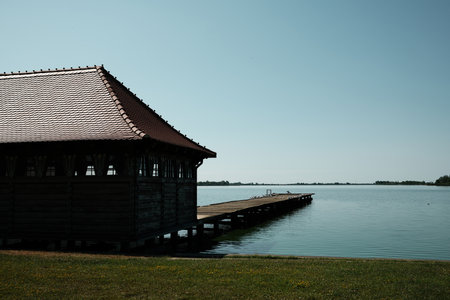 Traditional wooden lakeside building with a long pier stretching over the calm water of Palic Lake in Serbia. Lots of seagulls on a wooden pierの写真素材