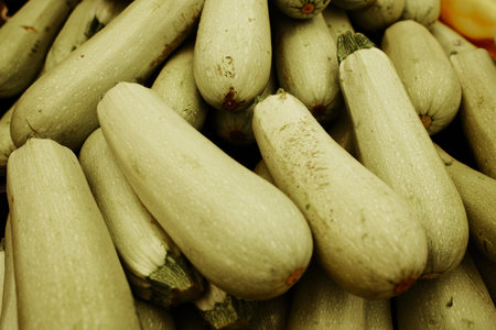 Fresh green zucchinis piled at the market. Organic farm vegetables used for cooking, grilling, and vegetarian mealsの写真素材