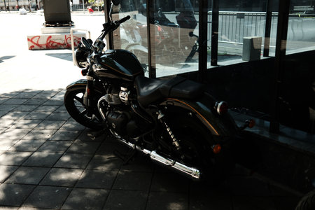 Black cruiser motorcycle parked by a glass building wall in the city, reflecting urban lifestyle. Belgrade, Serbiaの写真素材