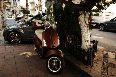 Brown retro-style scooter with windshield parked on city sidewalk under a tree. Belgrade, Serbiaの写真素材