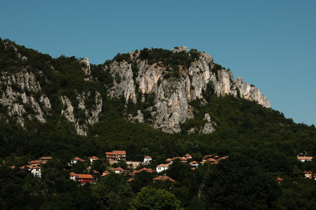 Traditional Serbian village with red rooftops nestled below dramatic rocky mountains in Stara Planinaの写真素材