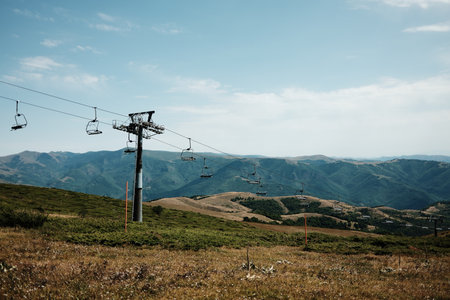 Empty chairlift rising above the green slopes of Stara Planina under a bright summer sky, with panoramic mountain views in the distance. Serbia countryの写真素材