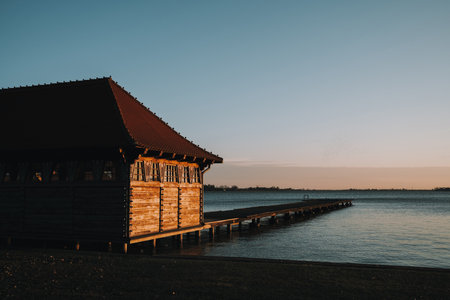 Wooden lakeside house and pier at Palic Lake, Serbia, in golden winter sunset lightの写真素材