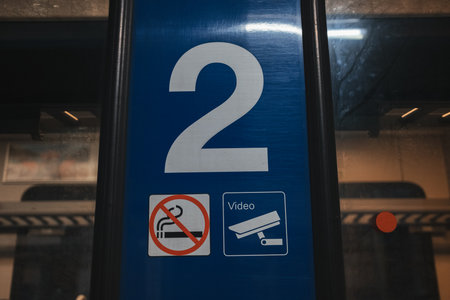 A close-up of a blue sign with the number 2, no smoking symbol, and CCTV camera icon on a Serbian trainの写真素材