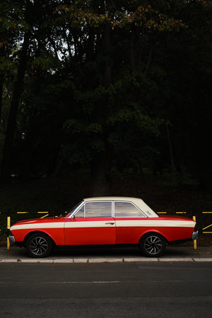 Vintage red and white classic car parked on Belgrade street near park and trees, side profileの写真素材