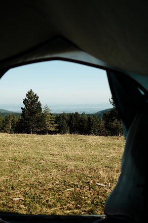 View from inside a tent looking out at the scenic Divcibare landscape in Serbia. Camping and outdoor adventure concept with mountains and treesの写真素材
