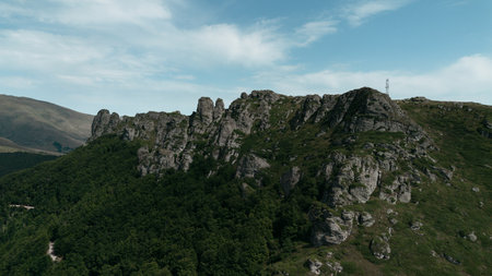 Rocky peaks of Babin Zub mountain in Stara Planina National Park, Serbia, rise above green forests under a blue sky. Aerial view from droneの写真素材