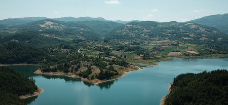 Beautiful aerial perspective of Rovni Lake in Serbia, with emerald water and forested shoreline. Surrounded by green hills and villagesの写真素材