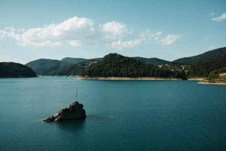 A lone rock with a cross rises from the blue waters of Zaovine Lake in Tara National Park, Serbiaの写真素材