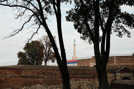 Pobednik statue rises above Kalemegdan Fortress walls framed by trees in Belgradeの写真素材