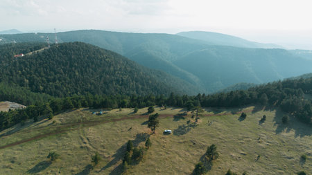 Aerial view of rolling green hills and open meadow in Divcibare, Serbia, with cars and people on the ridgeの写真素材