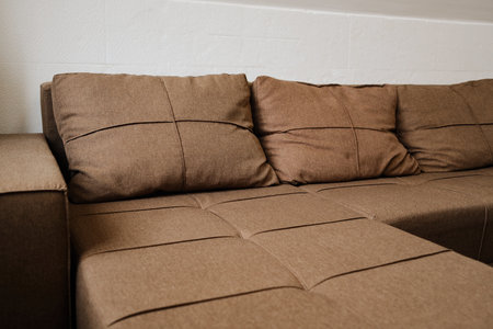 Close up of brown fabric sofa and cushions in a minimalist living room. Perfect for home design, furniture, and interior decoration projectsの写真素材