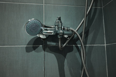 Close up of shower head and faucet in clean bathroom with gray tiles. Ideal for interior design, hygiene, and lifestyle visualsの写真素材