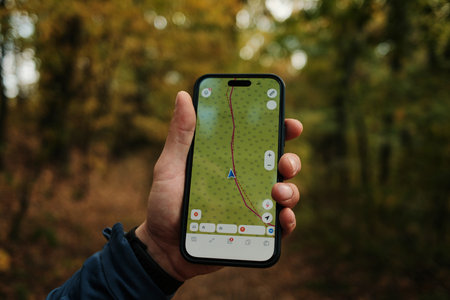 Close-up of man holding smartphone with GPS navigation app while hiking in autumn forest of Fruska Gora National Park Serbia. Travel conceptの写真素材