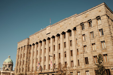 Historic post office building with stone columns and the dome of the National Assembly visible in...