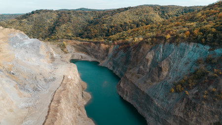 Aerial view of a flooded quarry surrounded by colorful autumn forest in Fruska Gora, Serbia. Calm...