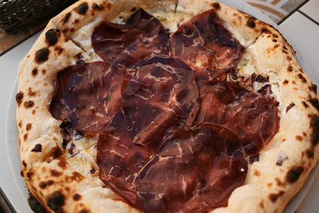 Juicy slices of prosciutto over creamy melted cheese on golden baked crust, irresistible Italian flavorの写真素材