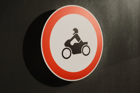 Round traffic sign prohibiting motorcycles on dark urban wall backgroundの写真素材