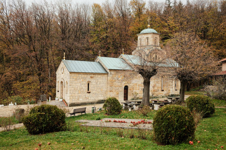 Old stone church surrounded by trimmed trees and colorful autumn vegetation. Monastery Tresije,...