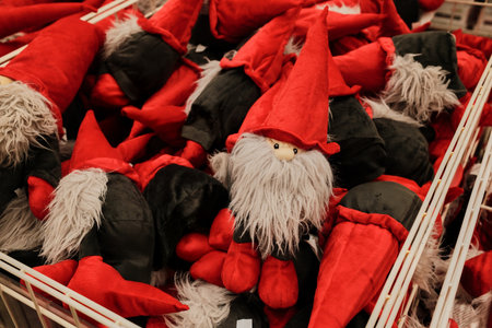 Red and gray plush gnomes with long beards displayed in a store basket. The concept represents holiday magic, coziness, and playful spiritの写真素材