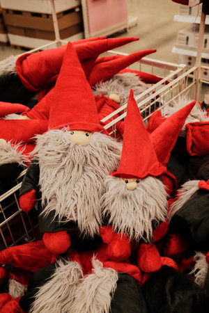 Red and gray plush gnomes with long beards displayed in a store basket. The concept represents holiday magic, coziness, and playful spiritの写真素材