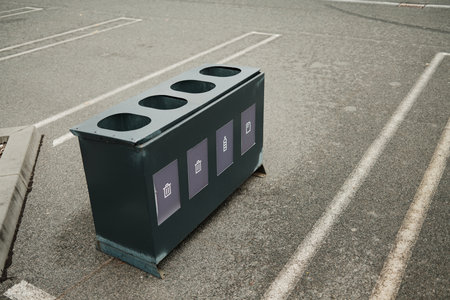 Black recycling bin with labeled sections for different waste types in parking area. The concept promotes sustainability, order, and modern designの写真素材