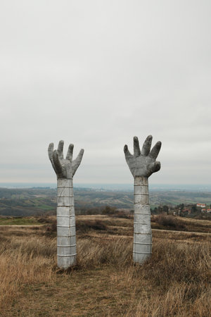 A metal hand sculpture rises above the open hills of Fruska Gora, contrasting human-made form with natural landscapeの写真素材