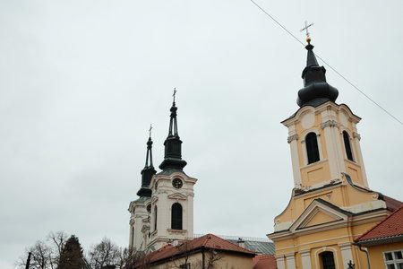 Twin baroque church towers in Sremski Karlovci, Serbia, rising over rooftops. A concept of religion,...
