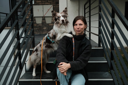 A Border Collie places its paw on the woman s shoulder as they sit on the steps. Concept conveys affection, trust, and emotional bonding between pet and ownerの写真素材