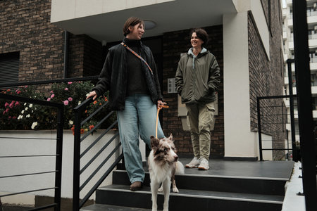 A woman walks downstairs with a border collie while her friend follows behind. The image shows movement and the concept of daily routineの写真素材