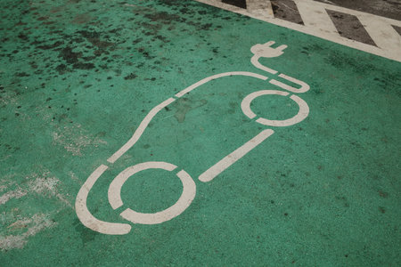 Electric car symbol painted on green pavement marking charging zone. Clean energy and sustainable transport concept with minimal urban designの写真素材