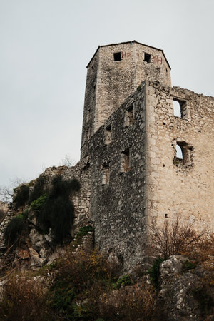 Stone tower of Pocitelj Fortress rising above rocky hillside in Bosnia and Herzegovina. Medieval defensive architecture surrounded by natural terrain and autumn vegetationの写真素材