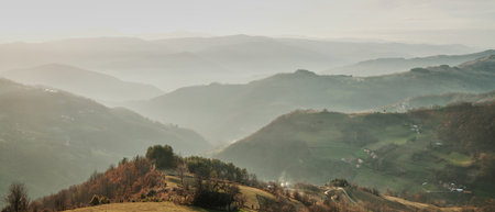 Misty mountain valley with rolling hills, forests, and scattered villages in Tara National Park,...