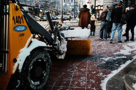 Municipal snow removal vehicle cleaning a sidewalk while people wait nearby. Belgrade, Serbia - 8...