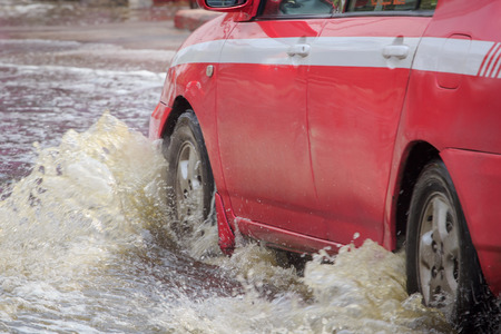 Car splashes through a large puddle on a flooded streetの写真素材
