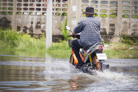 Splash by a motorcycle as it goes through flood waterの写真素材