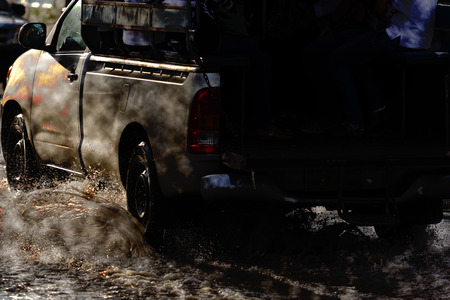 big water splash with car on flooded road after rainsの写真素材