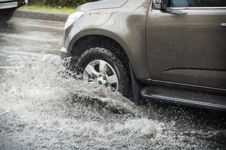 Splash by a car as it goes through flood waterの写真素材