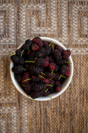 fresh blackberry in a bowl on the table, seen from above, bowl with fresh blueberries picked from the orchard, top view with natural textured background.の写真素材