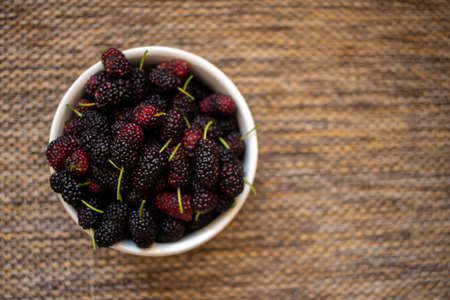 fresh blackberry in a bowl on the table, seen from above, bowl with fresh blueberries picked from the orchard, top view with natural textured background.の写真素材