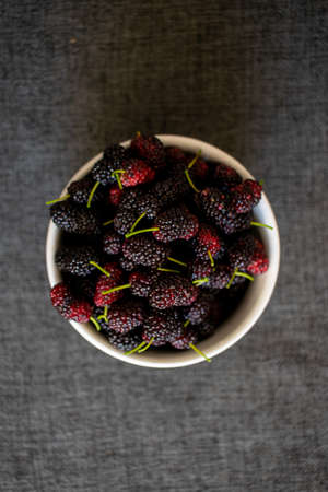 fresh blackberry in a bowl on the table, dark background viewed from above, white bowl with fresh blueberries viewed from above with dark background.の写真素材