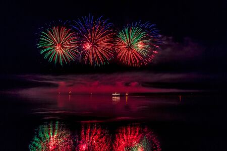 Bright festive fireworks reflected in the riverの写真素材