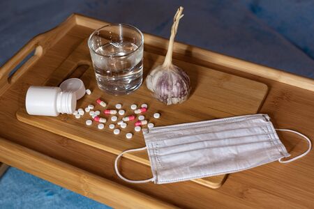 Concept, garlic and tablets, choice of treatment of the disease and medical maskの写真素材