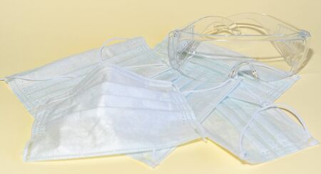 Protective medical masks and glasses on a yellow background flat lay top view.