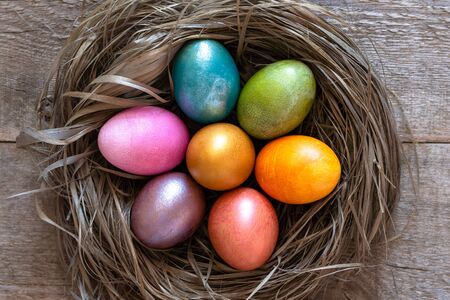 Beautiful multi-colored Easter eggs lie in a nest on a old wooden background, Easter holiday, copy spaceの写真素材