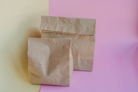 Paper bags with different food on a pink and yellow background, donation conceptの写真素材
