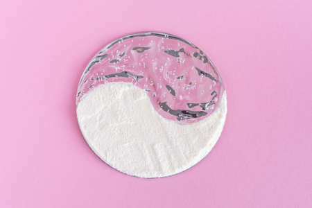 Collagen powder and cream gel cosmetic grease on a pink background. Internal and external cosmetic procedure for young skin and a healthy body. Creative yin yang concept. Flatlay, top view. Copyspace.の写真素材