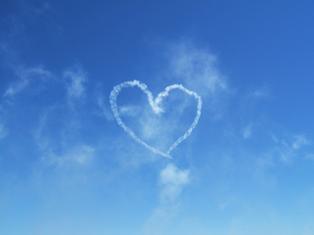 Heart in the sky made by airplane contrailの写真素材