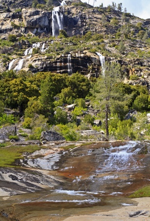 Tueeulala Falls cacades down clifffs before pouring down red rocks before falling into the Hetch Hetchy Reservoir in Yosemite National Park, Californiaの写真素材